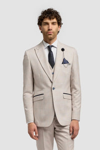 Vīrietis bēšā uzvalkā ar baltu kreklu un brūnām kurpēm uz gaiši pelēka fona